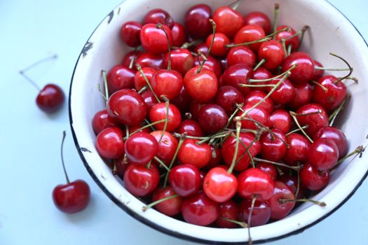 many ripe raw wet sweet cherry in dish on wooden background