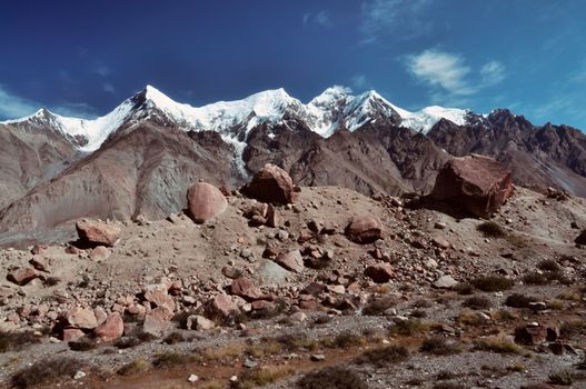 Large rocks on the edge of Engilchek glacier with picturesque Tian Shan mountain range in Kyrgyzstan