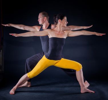 Young couple doing yoga. On the black backgraund