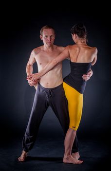 Young couple doing yoga. On the black backgraund