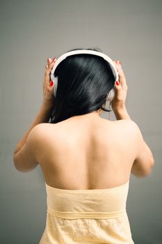 Beautiful Indian girl listening and enjoying music over headphone