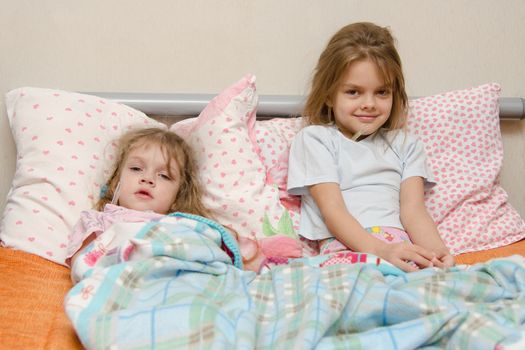 Two girls and four to six years lying in bed meryat temperature thermometer
