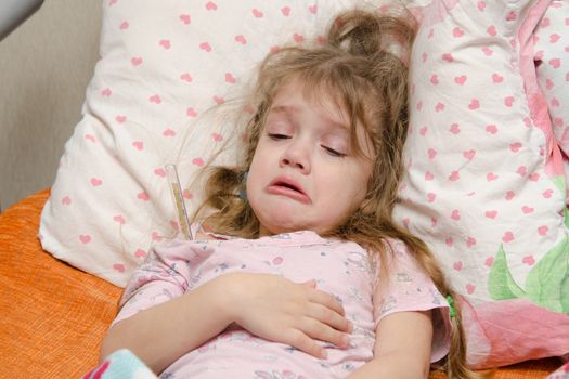 The three-year diseased girl lying in bed, Meria temperature thermometer, in a bad mood