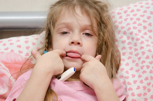 The three-year diseased girl lying in bed, Meria temperature thermometer, in a bad mood