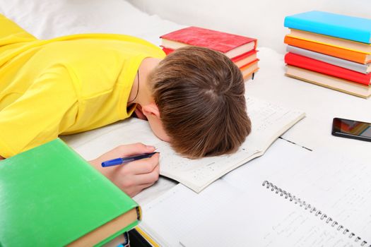 Sad and Tired Teenager doing Homework at the Home