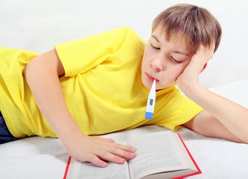 Sick Kid with a Book and Thermometer on the Bed