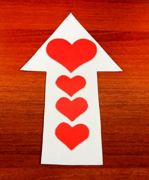 Red Heart Shapes on the Arrow and on the Wooden Background