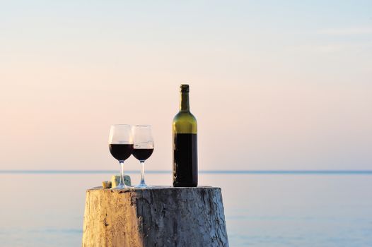 Red wine bottle and wine glasses on the wooden stump