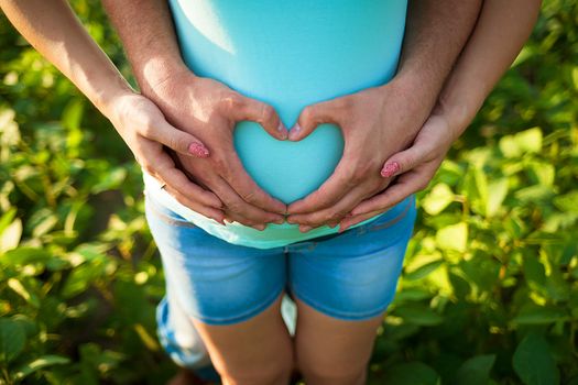 Man's hands embrace a belly of the pregnant woman.