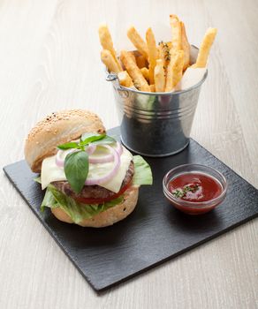 Healthy wheat sandwich burger with beef steak, cheese, tomato, lettuce, onion, basil, fried potato and ketchup  served for eating