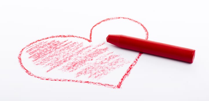 Closeup of a red pencil drawing a heart. On white paper.