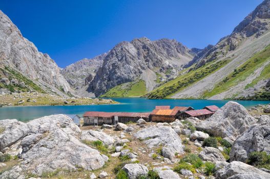 Mountain huts by crystal clear lake in mountain range Tien-Shan in Kyrgyzstan