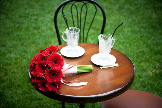 red bridal bouquet and cappuccino, coffee cup on table