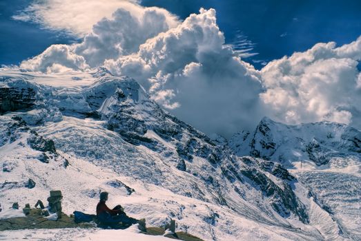 Young hiker sitting in south american Andes in Peru, Ausangate with dramatic clouds forming above the mountains