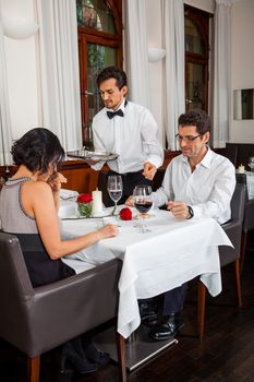 Waiter happily accommodating couple with a big smile on his face