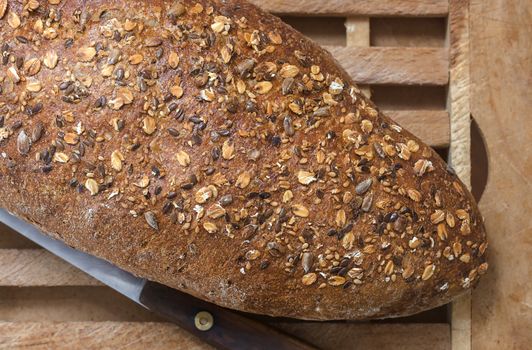 Whole Grain Bread and Vintage Knife on Wooden Cutting Board  detail