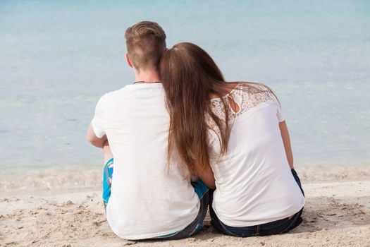 romantic young couple sitting on the beach in summer holiday vacation love