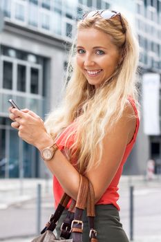Girl smiling while texting in the street