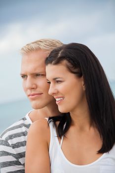 Loving couple enjoy a quiet tender moment as they stand in a close embrace staring off to the left of the frame in contentment