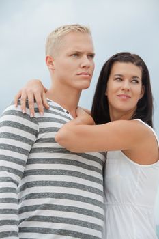 Loving couple enjoy a quiet tender moment as they stand in a close embrace staring off to the left of the frame in contentment