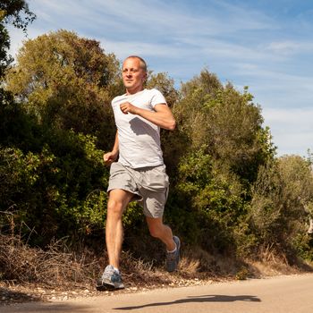 athletic man runner jogging in nature outdoor fitness summer healthy