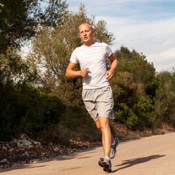 athletic man runner jogging in nature outdoor fitness summer healthy