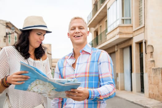 Trendy attractive young couple of tourists consulting a map as they search for their destination while out sightseeing on their summer vacation