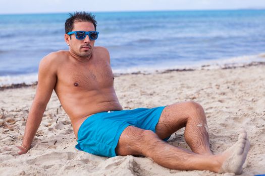 attractive young athletic man on the beach in summer outdoor vacation