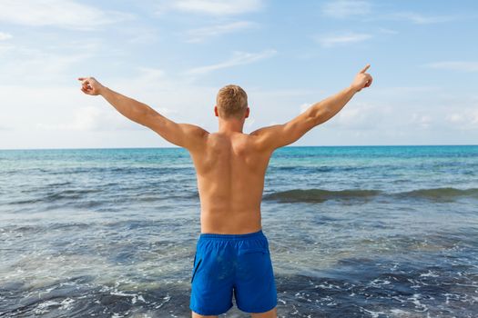 Man in blue swim shorts standing proud in the beach