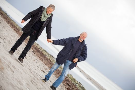 mature happy couple walking on beach in autumn lifestyle healthy