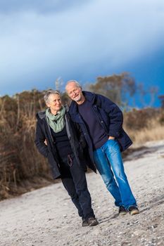 mature senior couple walking on the beach autumn winter lifestyle healthy