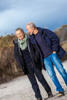 mature senior couple walking on the beach autumn winter lifestyle healthy