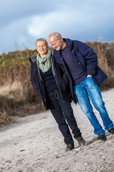 mature senior couple walking on the beach autumn winter lifestyle healthy