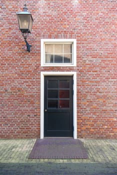 Vintage black door in front of the house with classic style lamp