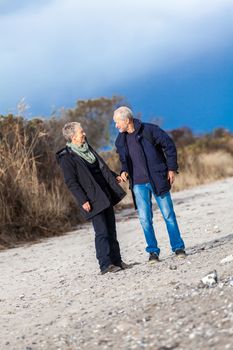 mature senior couple walking on the beach autumn winter lifestyle healthy