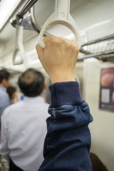 Hand of passengers hold on rail handle of transit system, train