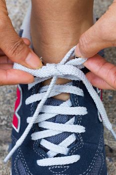 sport, fitness, exercise and lifestyle concept - runner woman lacing trainers shoes, closeup.