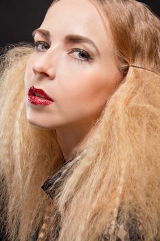 Beautiful seductive blond woman with red parted lips and a sultry expression looking sideways at the camera with an inviting glance