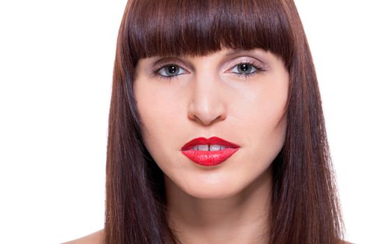 Beautiful seductive woman with her brunette hair cut in bangs and a sultry look with parted lips and her hand raised to her face, close up facial portrait looking directly at the camera