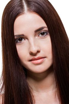 Beautiful serene young woman with a gentle expression, bare shoulders and long straight brown hair looking calmly at the camera , close up side view with turned head isolated on white