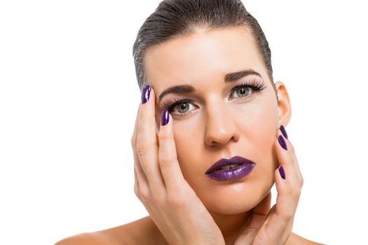 Graceful naked woman with purple lips and nails in a pensive pose with a serene expression and downcast eyes in a beauty and glamour portrait , isolated on white