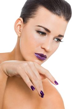 Graceful naked woman with purple lips and nails in a pensive pose with a serene expression and downcast eyes in a beauty and glamour portrait , isolated on white