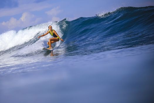 Surfer girl on Amazing Blue Wave, Bali island.