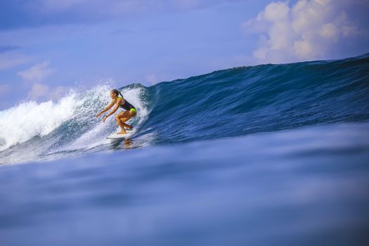 Surfer girl on Amazing Blue Wave, Bali island.