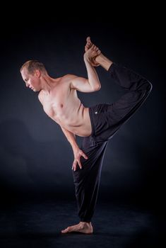 Handsome man doing yoga. Shot on black background