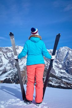 Ski, winter, snow, skiers, sun and fun - Back view of Middle Aged Woman On Ski Holiday In Mountains
