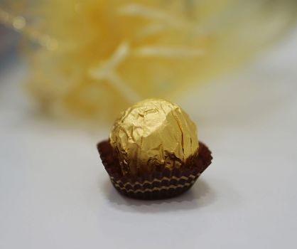 Round chocolate wrapped in gold foil paper, placed in the base paper circle.                              