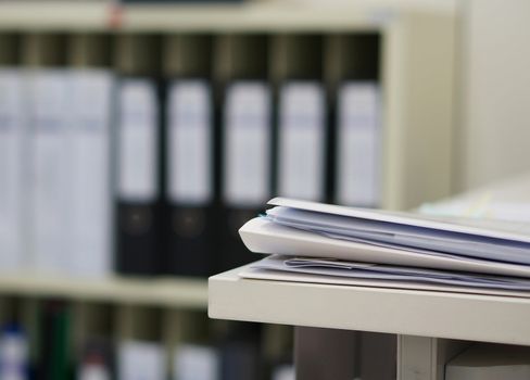 Many papers orderly arranged in a file shelves. And some are still on the table.                               