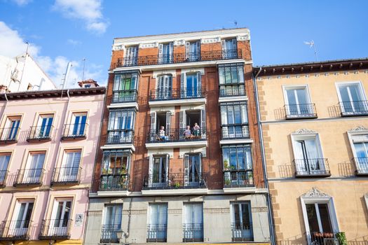 Madrid, Spain - May 6, 2012: Young girls on balconies of a typical building facade on a street of Madrid, Spain
