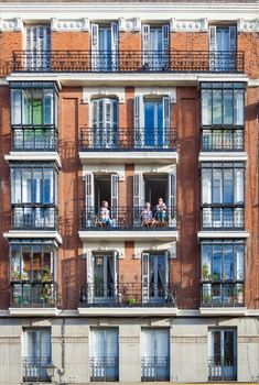 Madrid, Spain - May 6, 2012: Young girls on balconies of a typical building facade on a street of Madrid, Spain